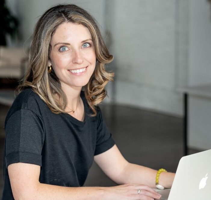 A woman sitting at a desk with a laptop.